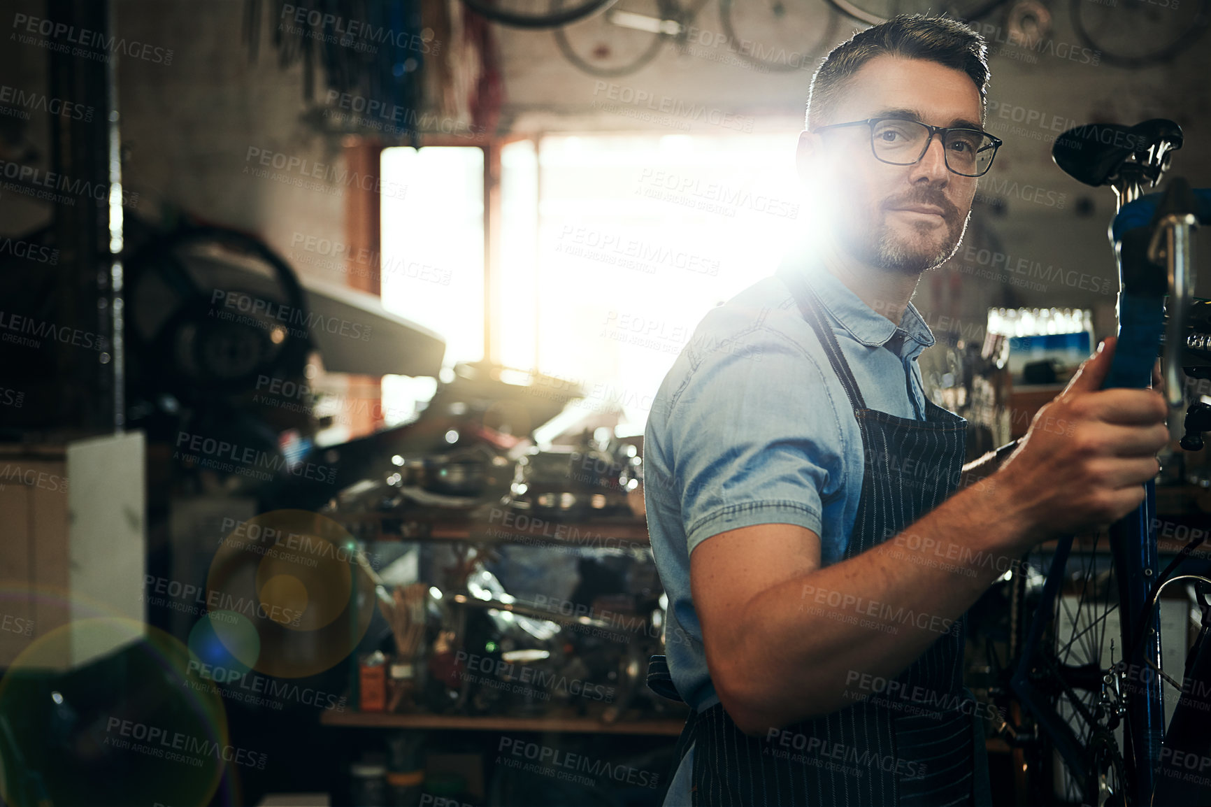 Buy stock photo Man, portrait and bicycle mechanic with inspection for fix or maintenance at repair shop. Young male person or expert working on bike parts with tools or equipment for service at workshop or garage