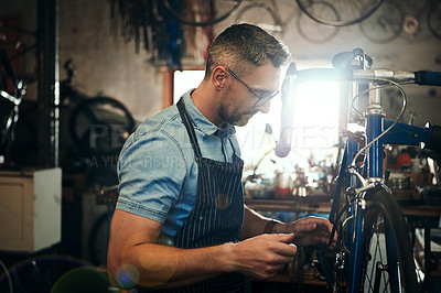 Buy stock photo Shot of a mature man working in a bicycle repair shop