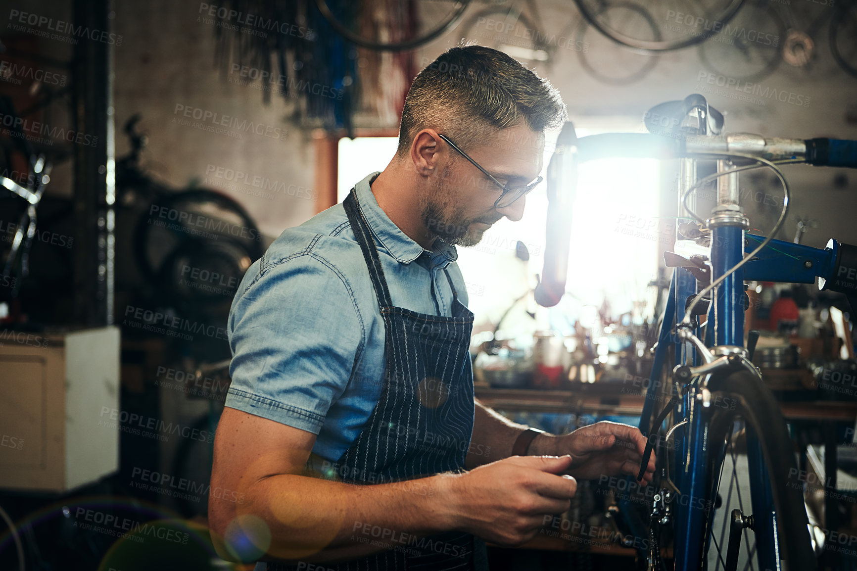 Buy stock photo Man, bicycle and mechanic with wheel for repair, fix or maintenance at indoor workshop. Young male person, cycle technician or bike engineer working on cycling vehicle, gears or hardware at shop