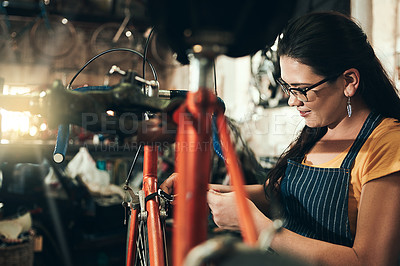 Buy stock photo Woman, bicycle technician and fix with inspection for maintenance, skill or trade at repair shop. Young female person, cycling mechanic or engineer working on bike with tools or equipment at workshop