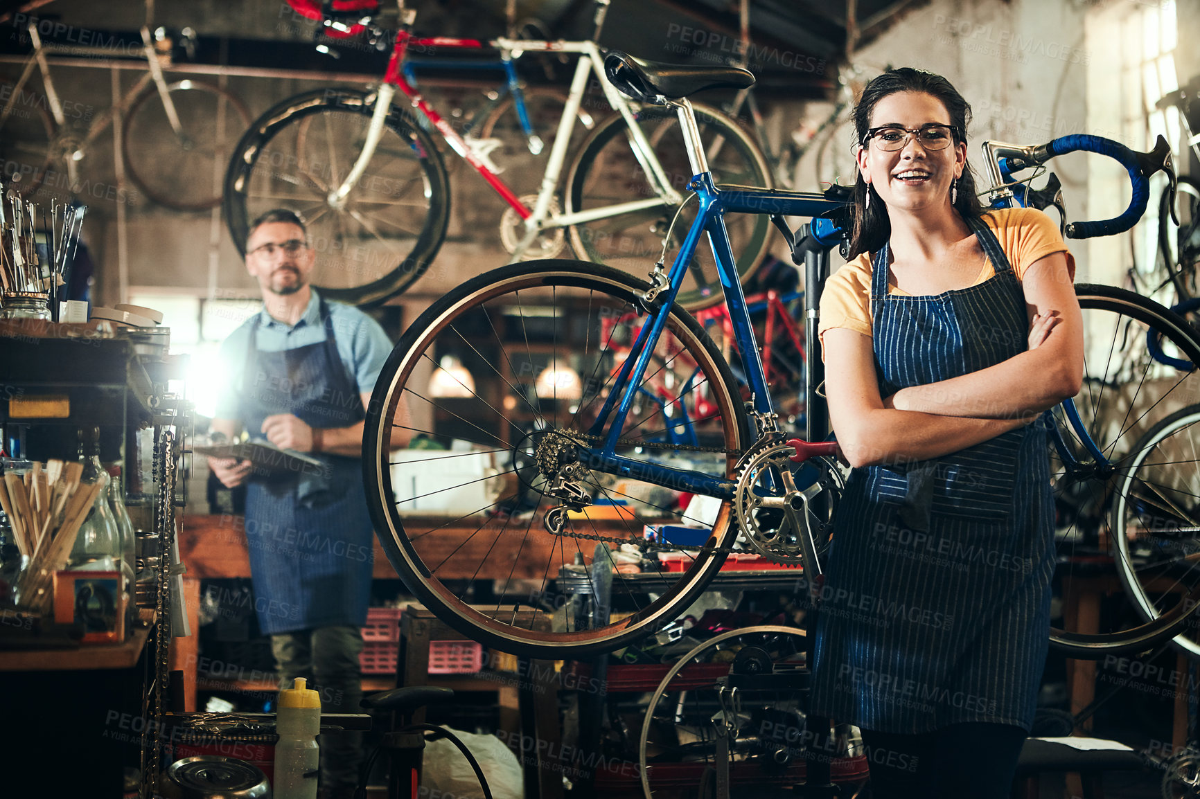 Buy stock photo Woman, portrait with arms crossed at bicycle repair shop for work in maintenance garage and smile. Bike, mechanic and service with professional coworker for startup, small business and workshop