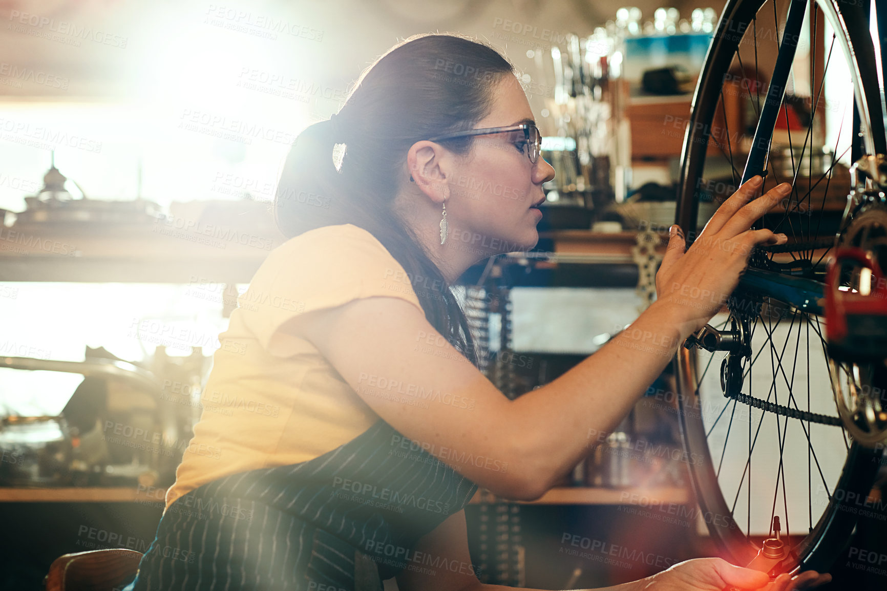 Buy stock photo Bicycle technician, working and repair in shop with frame, chain and tools for maintenance or cycling. Woman, bike and mechanic in workshop as handyman for gear, inspection and safety with glasses