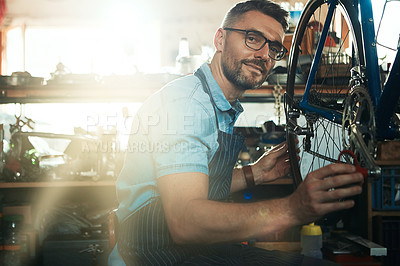 Buy stock photo Man, garage and smile as bicycle mechanic with lens flare in startup or small business. Workshop, portrait and happy or confident as handyman with fixing bike at repair or maintenance shop and proud