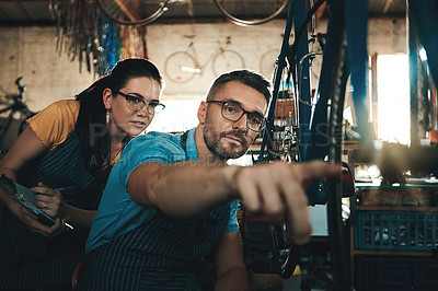 Buy stock photo Bicycle technician, working and repair in shop with chains, frame and tools for maintenance or cycling. Man, bike and mechanic in workshop as teamwork for gear, inspection and safety with glasses