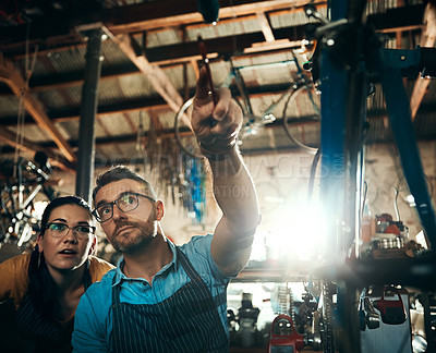 Buy stock photo Shot of a man and woman working together in a bicycle repair shop