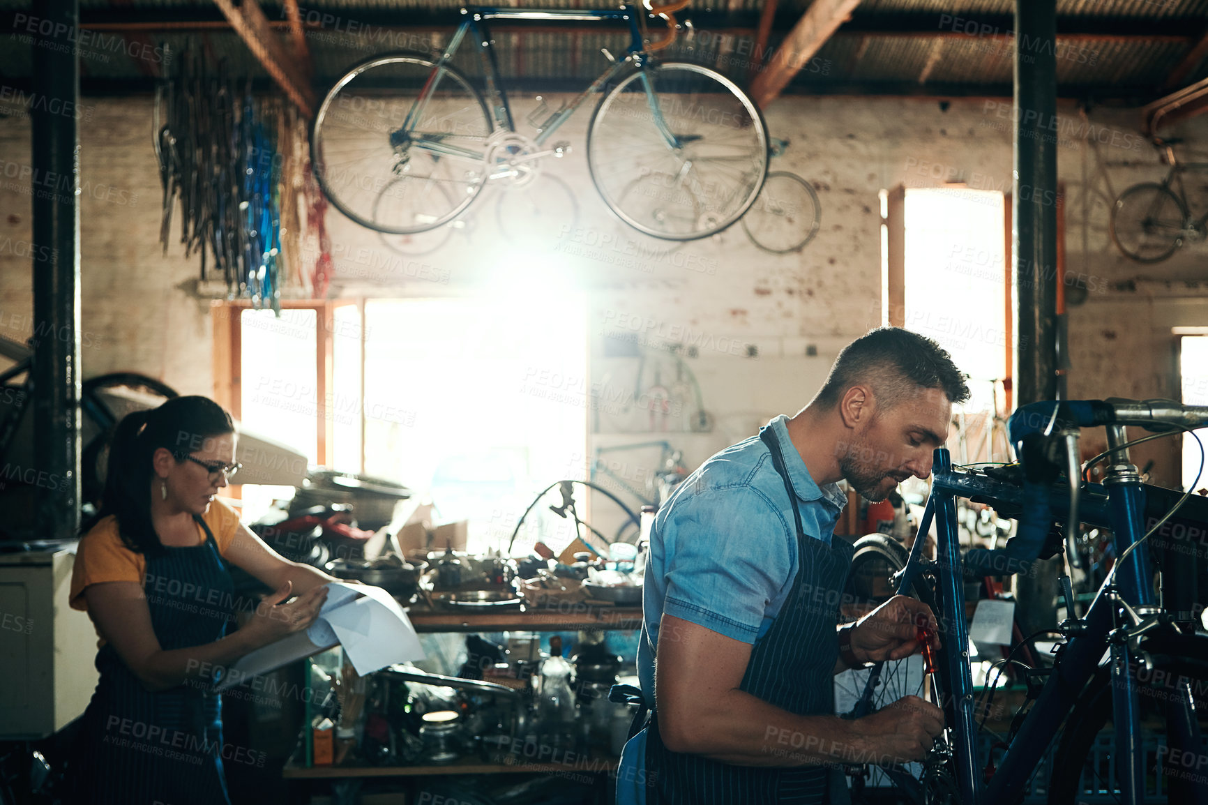 Buy stock photo Bicycle technician, repair and working in shop with frame, chain and tools for maintenance or cycling. Mechanic, bike and teamwork in workshop as handyman for gear, inspection and safety with woman