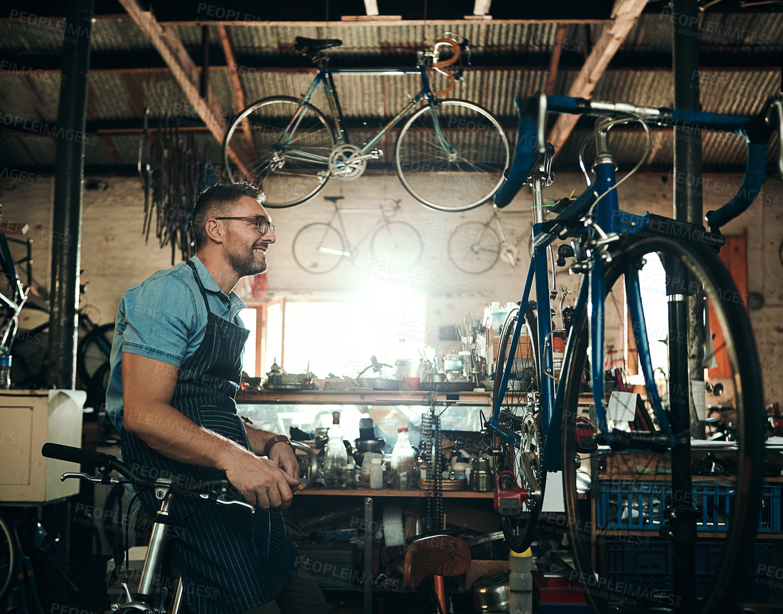 Buy stock photo Bicycle technician, planning and working in shop with frame, chain and tools for maintenance or cycling. Mechanic, bike and man in workshop as handyman for gear, inspection and safety with glasses