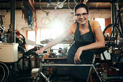 Buy stock photo Portrait of a young woman working in a bicycle repair shop