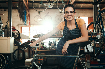 Buy stock photo Portrait of a young woman working in a bicycle repair shop