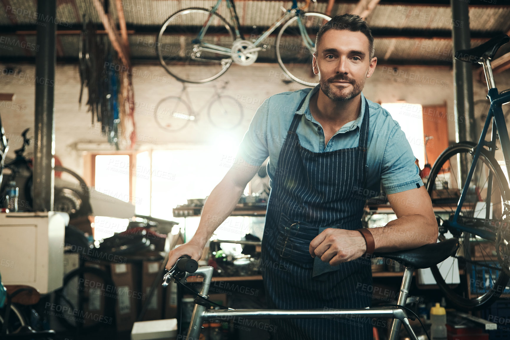 Buy stock photo Man, bicycle shop and portrait for maintenance job, startup with transport service. Bike, mechanic and male entrepreneur in workshop with glasses, happiness for sustainable business with apron