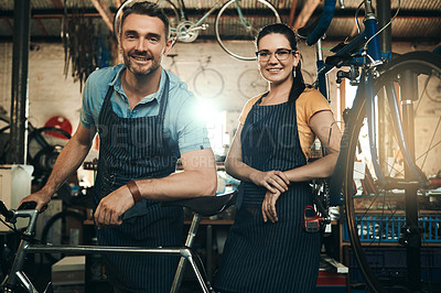 Buy stock photo Portrait of a man and woman working together in a bicycle repair shop