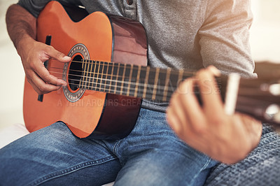 Buy stock photo Shot of an unrecognizable man practising guitar at home