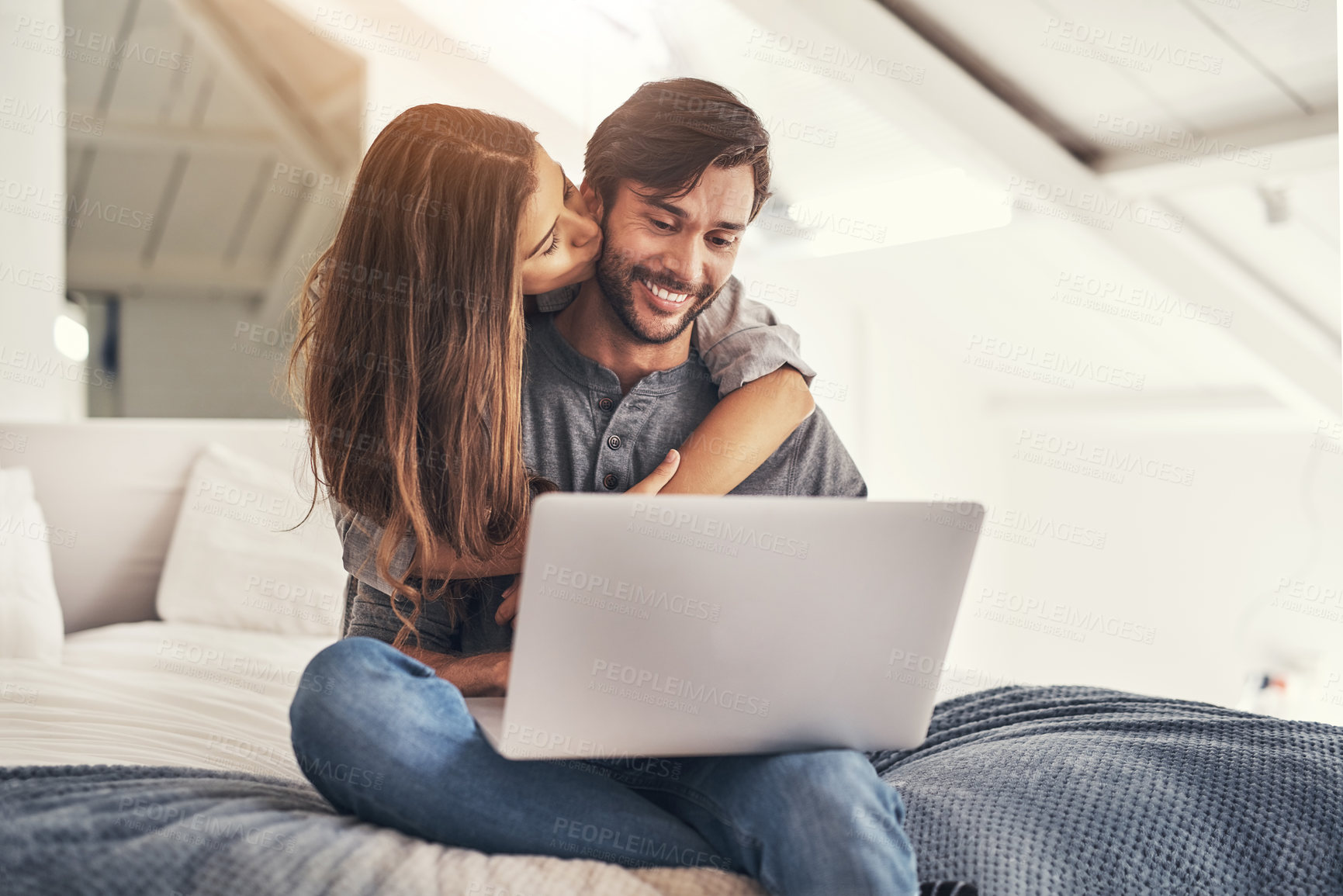 Buy stock photo Couple, laptop and kiss or hug in bedroom with online search for holiday destination or discount offers on travel. People, happy and embrace on bed in home with romance, social media browsing or love