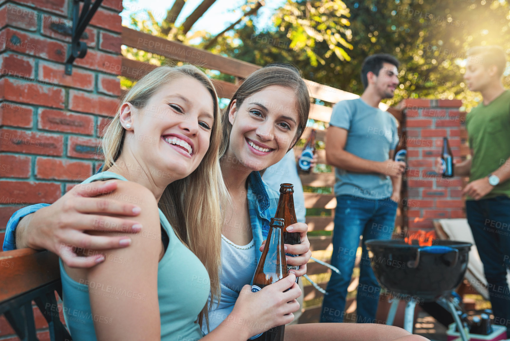 Buy stock photo Shot of two happy young women enjoying some beers at a barbecue with their friends