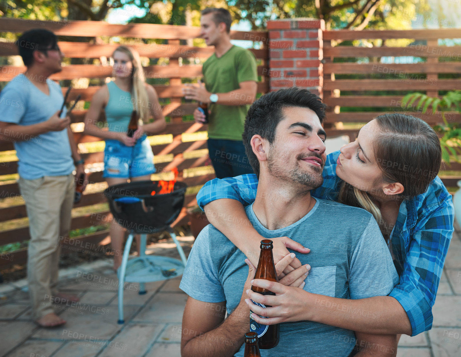 Buy stock photo Couple, playful and barbecue outdoor with friends, drinks and fire for fun social event on weekend. Man, woman and bbq in backyard with hug, people and bonding for labor day, celebration and holiday