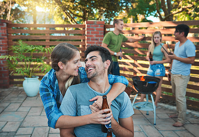 Buy stock photo Shot of an affectionate young couple enjoying themselves at a barbecue with friends