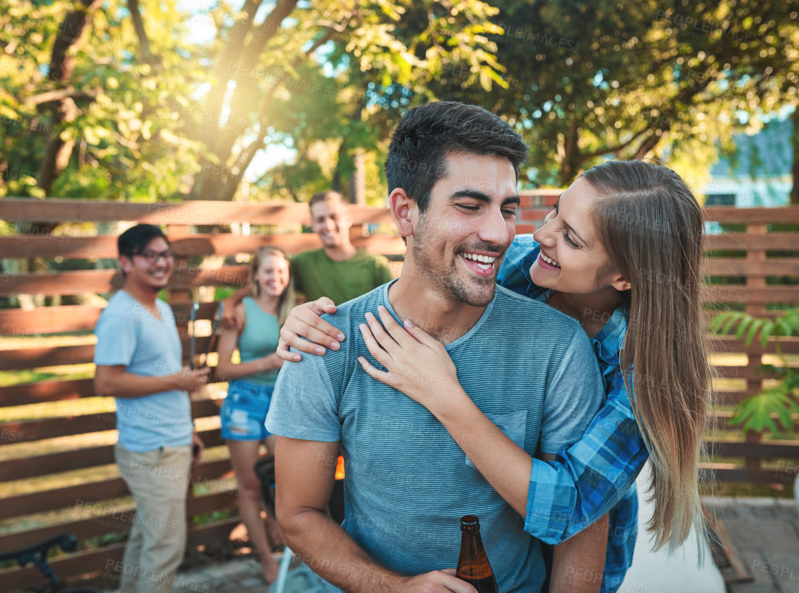Buy stock photo Couple, happiness and barbecue outdoor with friends, drinks and fire for fun social event on weekend. Man, woman and bbq in backyard with hug, people and bonding for reunion, celebration and holiday