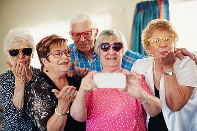 Buy stock photo Shot of a group of seniors taking a selfie indoors