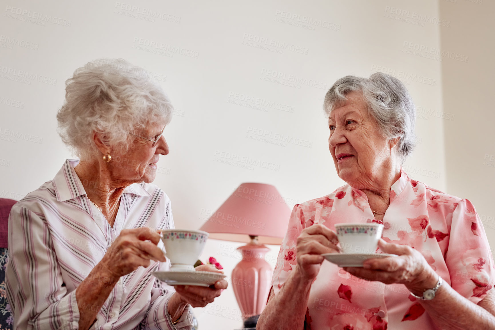 Buy stock photo Shot of two happy elderly women having tea together at home