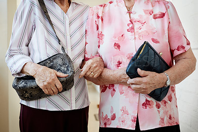 Buy stock photo Cropped shot of two elderly women holding their bags and linking arms