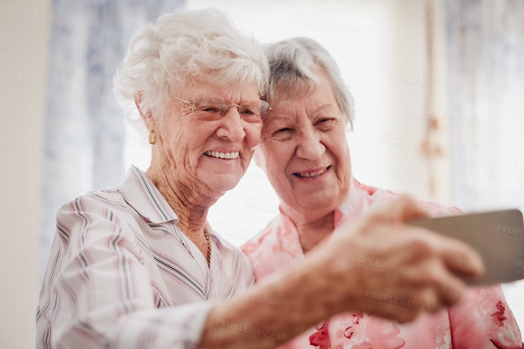 Buy stock photo Portrait of two happy elderly women taking selfies together on a mobile phone
