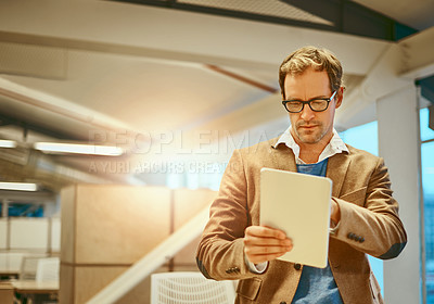 Buy stock photo Cropped shot of a handsome male designer working on a tablet in his office