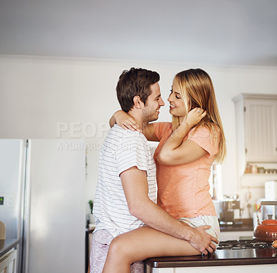 Buy stock photo Shot of a happy young couple sharing a romantic moment in the kitchen at home