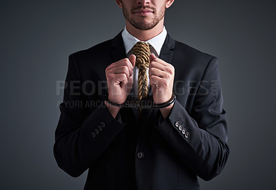 Buy stock photo Studio shot of a handcuffed businessman with a noose tied around his neck for a tie against a gray background