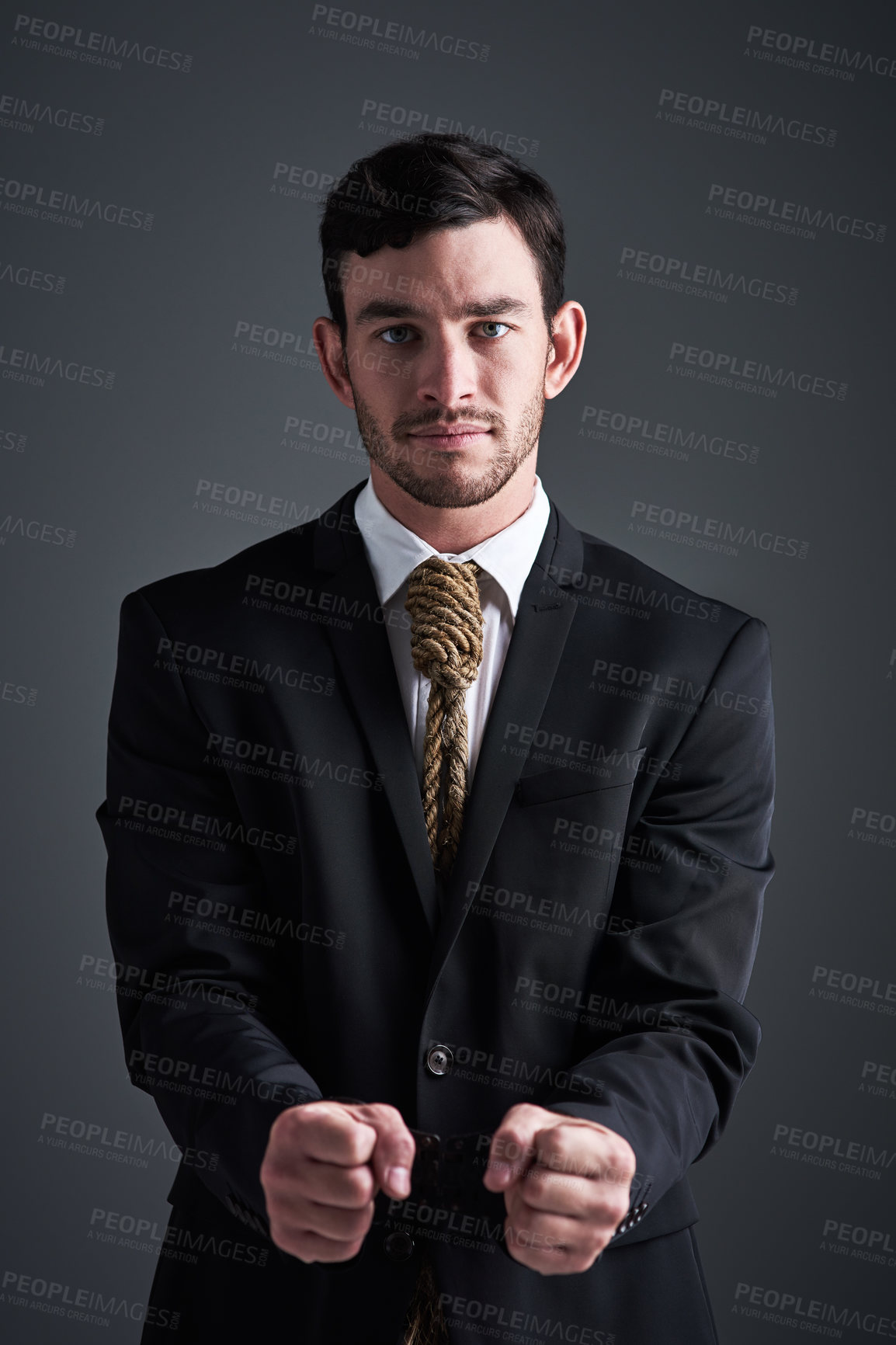 Buy stock photo Studio portrait of a handcuffed businessman with a noose tied around his neck for a tie against a gray background