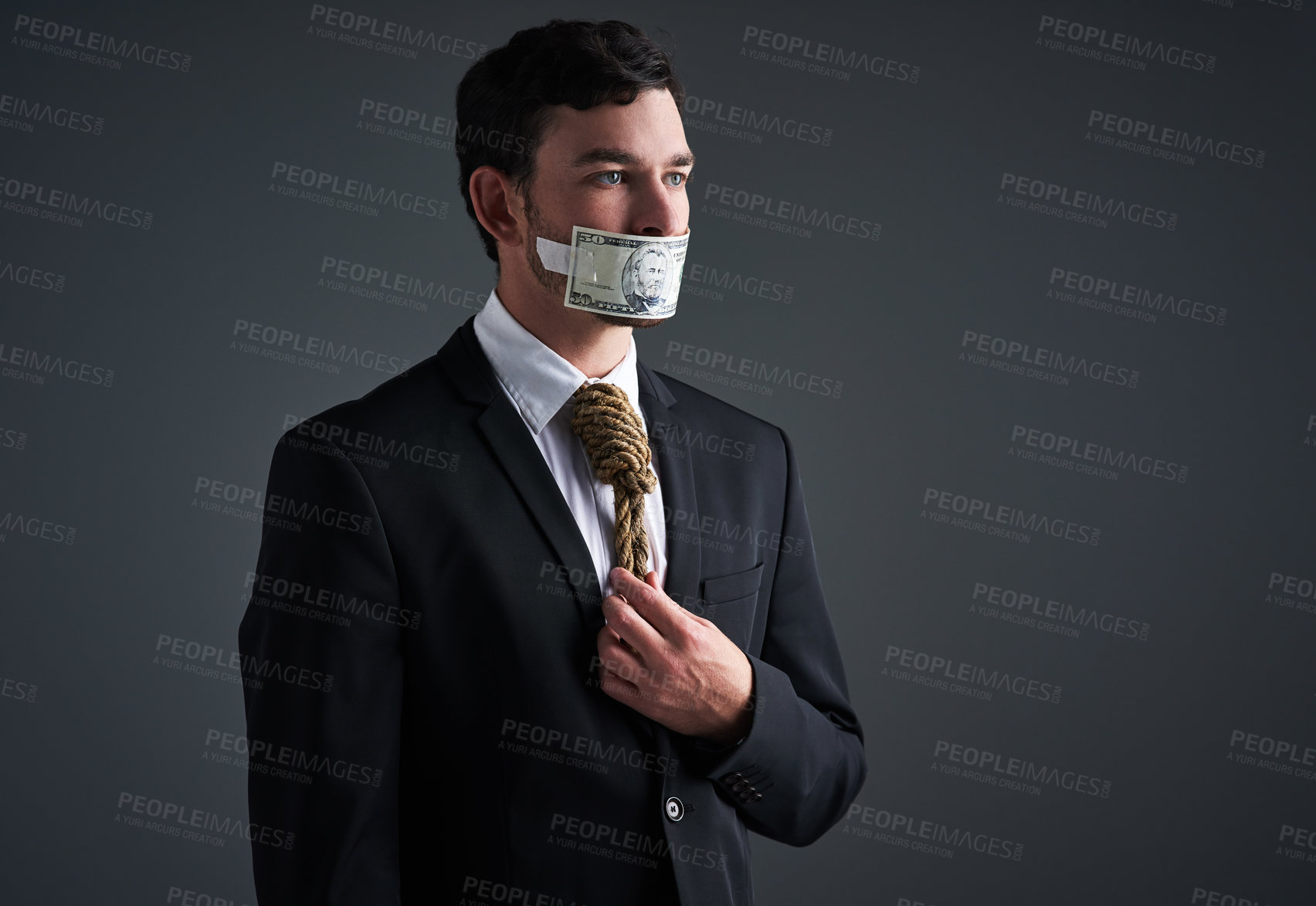 Buy stock photo Studio shot of a businessman with rope around his neck and money taped over his mouth against a gray background