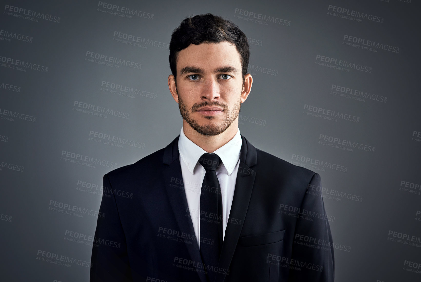 Buy stock photo Studio portrait of a handsome young businessman dressed in a suit against a grey background