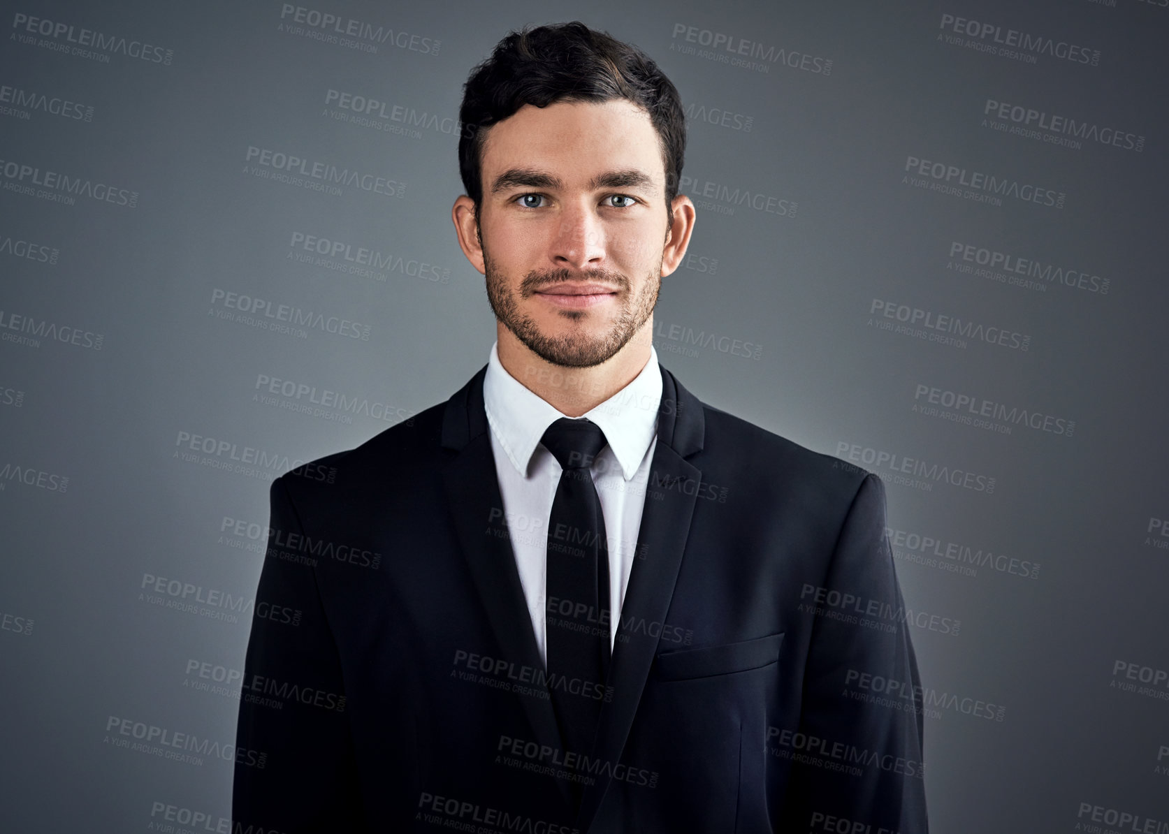 Buy stock photo Studio portrait of a handsome young businessman dressed in a suit against a grey background