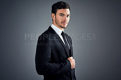 Buy stock photo Studio portrait of a handsome young businessman dressed in a suit against a grey background