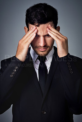 Buy stock photo Studio shot of a young businessman suffering from a headache against a grey background