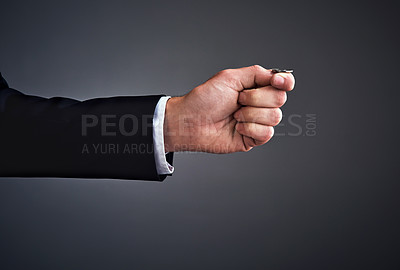 Buy stock photo Cropped studio shot of a businessman’s hand flipping a coin against a gray background