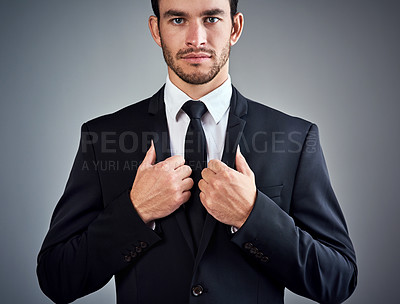 Buy stock photo Studio portrait of a handsome young businessman dressed in a suit against a grey background