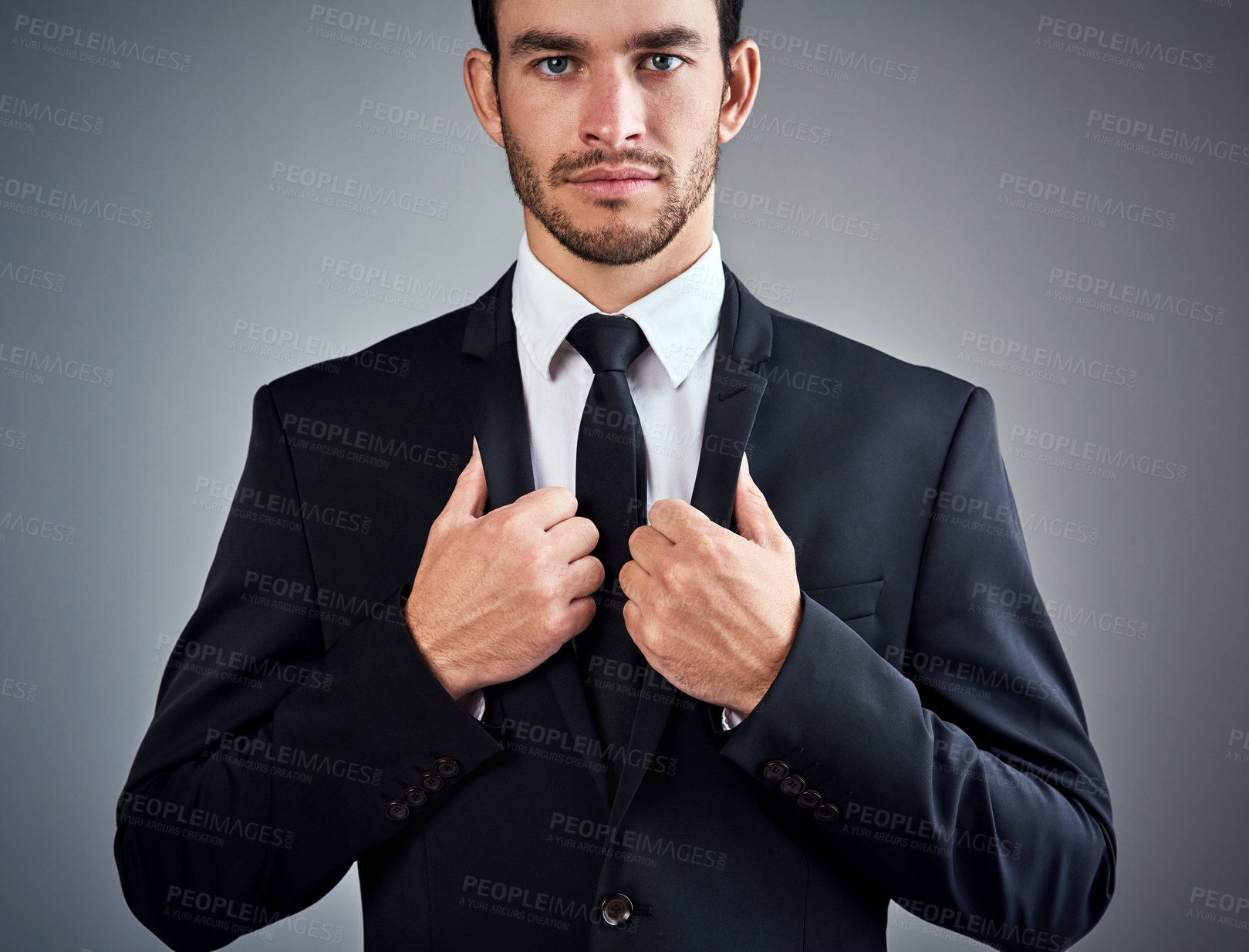 Buy stock photo Studio portrait of a handsome young businessman dressed in a suit against a grey background