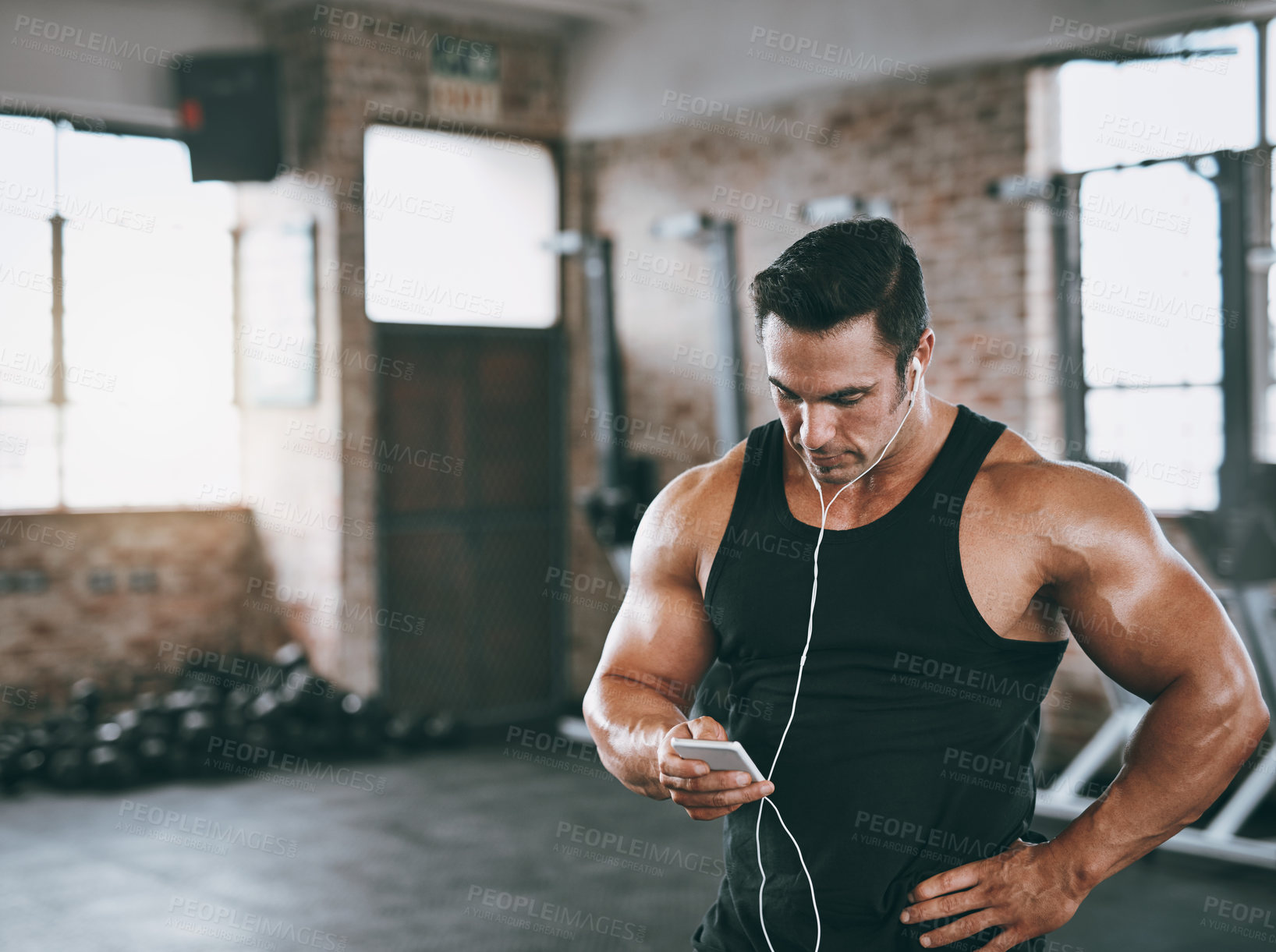 Buy stock photo Shot of a man listening to music at the gym