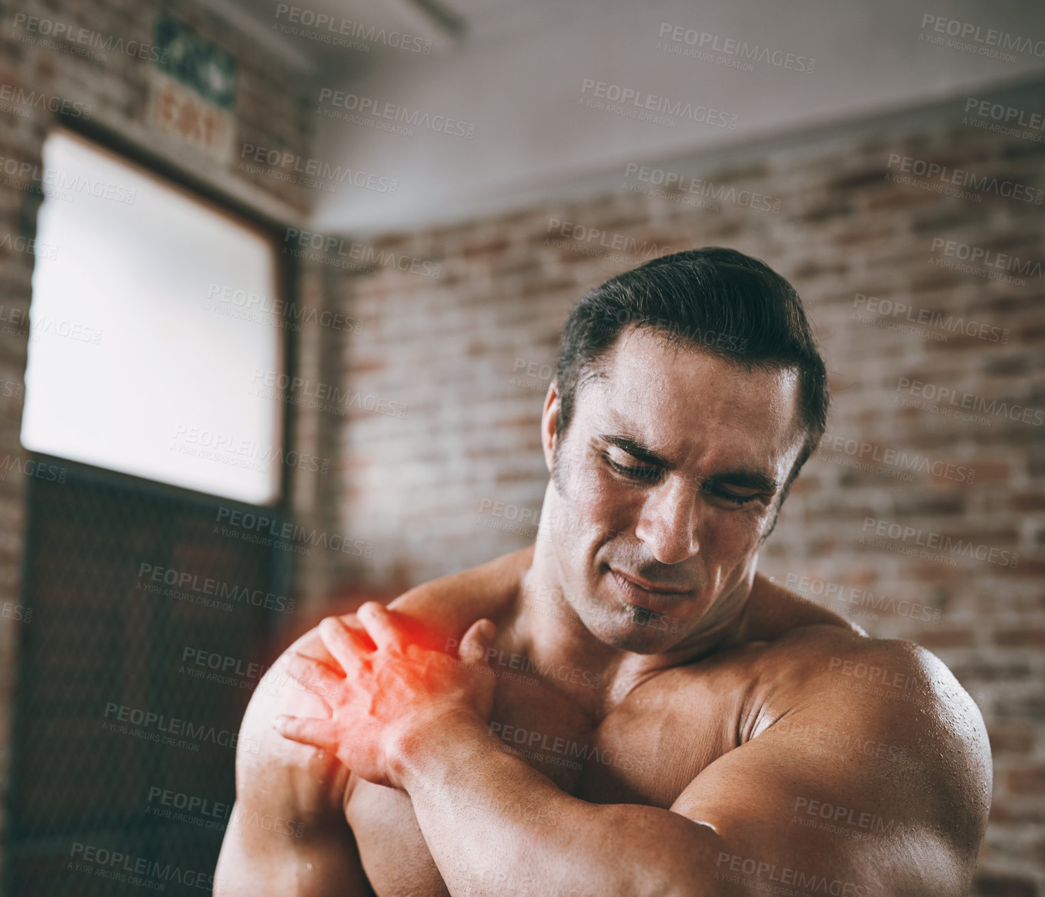 Buy stock photo Shot of a man suffering from a shoulder injury at the gym