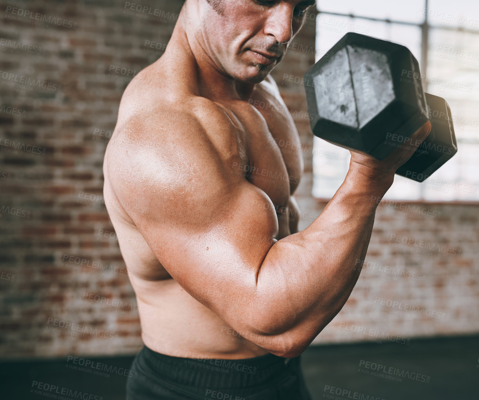 Buy stock photo Shot of a young man working out with dumbbells at the gym