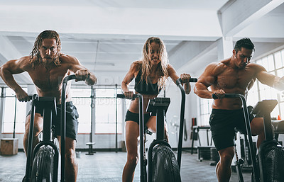 Buy stock photo Shot of three people working out on elliptical machines