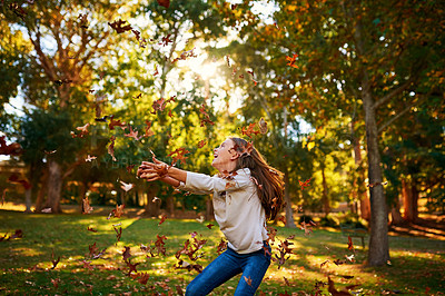 Buy stock photo Shot of a happy little girl playing in the autumn leaves outdoors