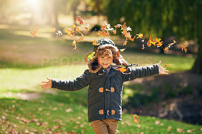Buy stock photo Shot of a happy little boy playing in the autumn leaves outdoors