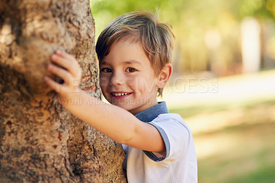 Buy stock photo Shot of a happy little boy playing next to a tree in the park