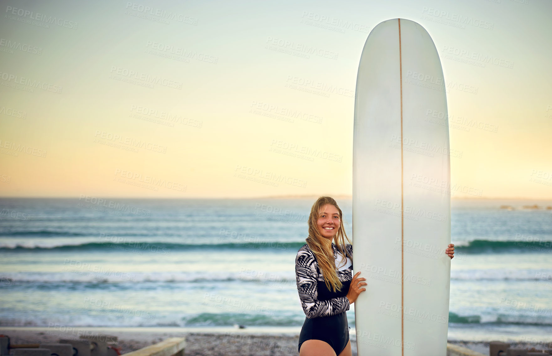 Buy stock photo Cropped portrait of an attractive young female surfer standing with her surfboard on the beach