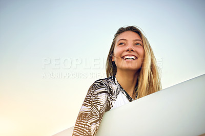 Buy stock photo Low angle shot of an attractive young female surfer standing with her surfboard on the beach