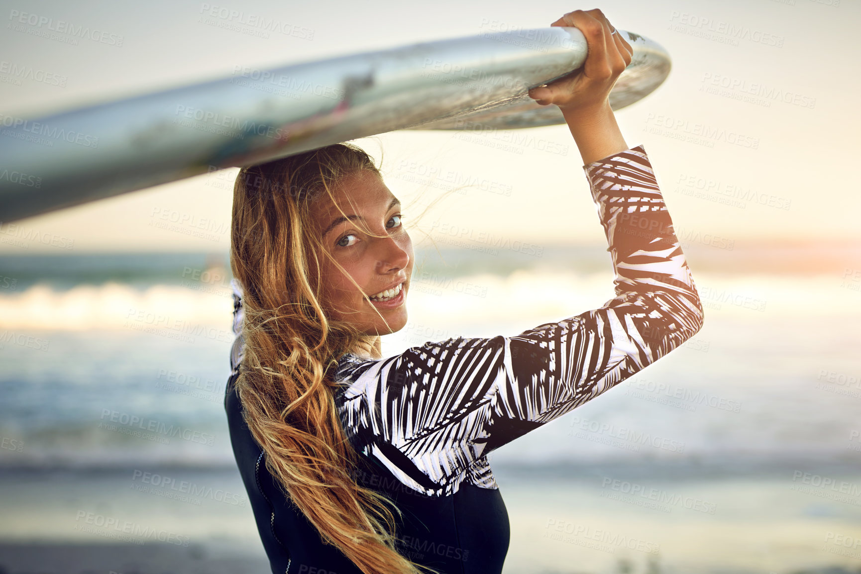 Buy stock photo Rearview portrait of an attractive young female surfer standing with her surfboard looking over the ocean