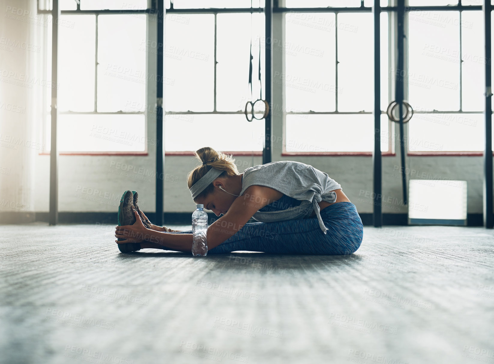 Buy stock photo Shot of a young attractive woman stretching in a gym