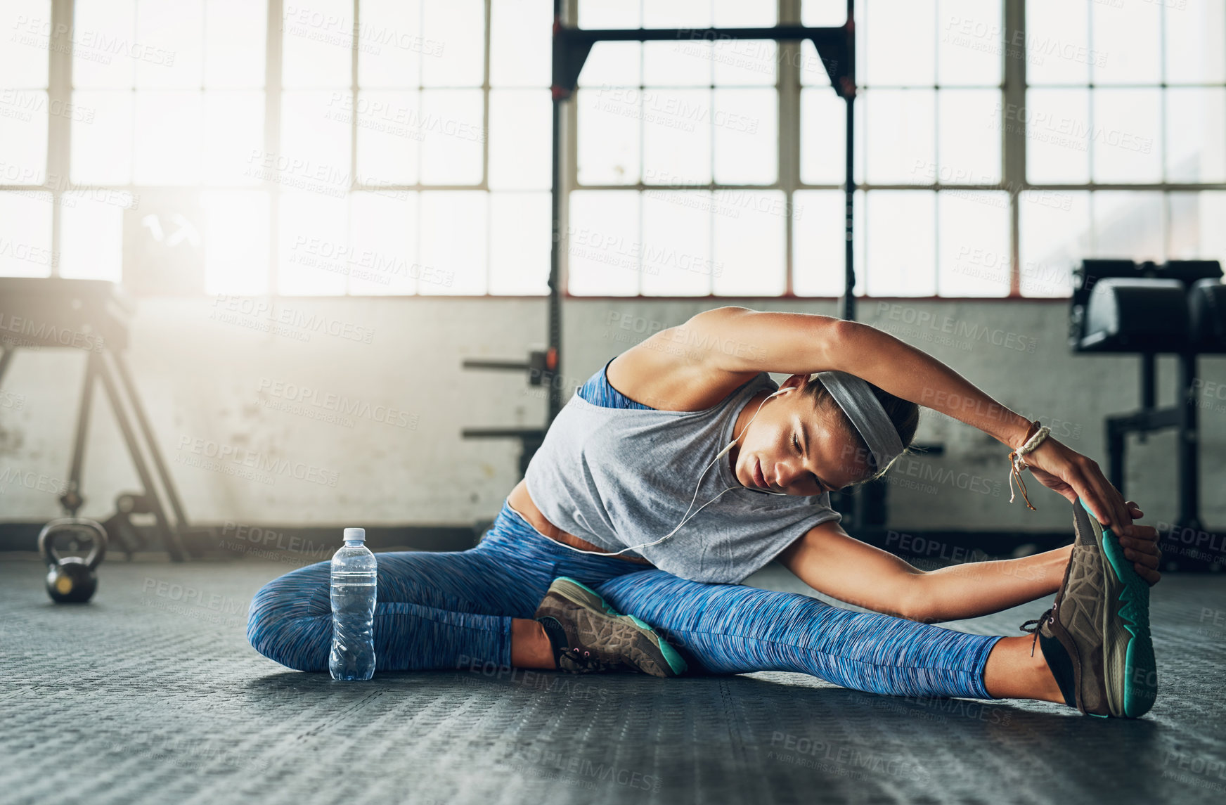 Buy stock photo Shot of a young attractive woman stretching in a gym