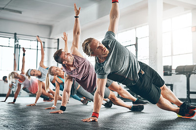 Buy stock photo Gym class, group and athletes doing a workout for fitness, health or wellness flexibility. Sports, community and people doing a side plank exercise, training or challenge together in a sport studio.